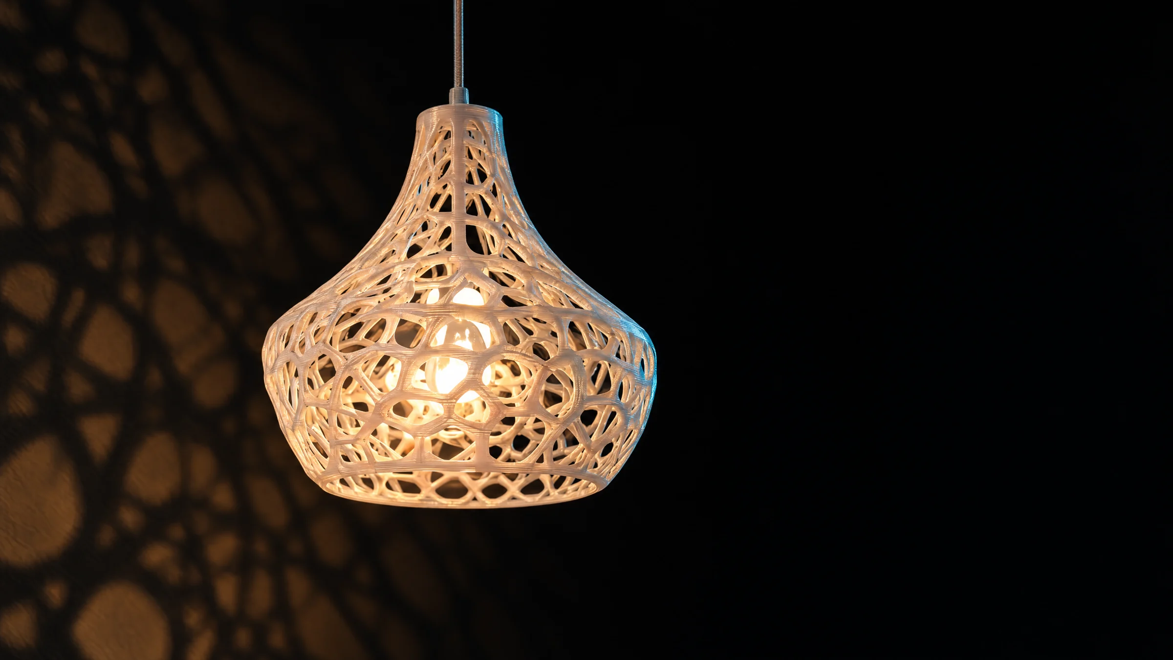 Pendant lamp with a 3D printed perforated shell, switched on