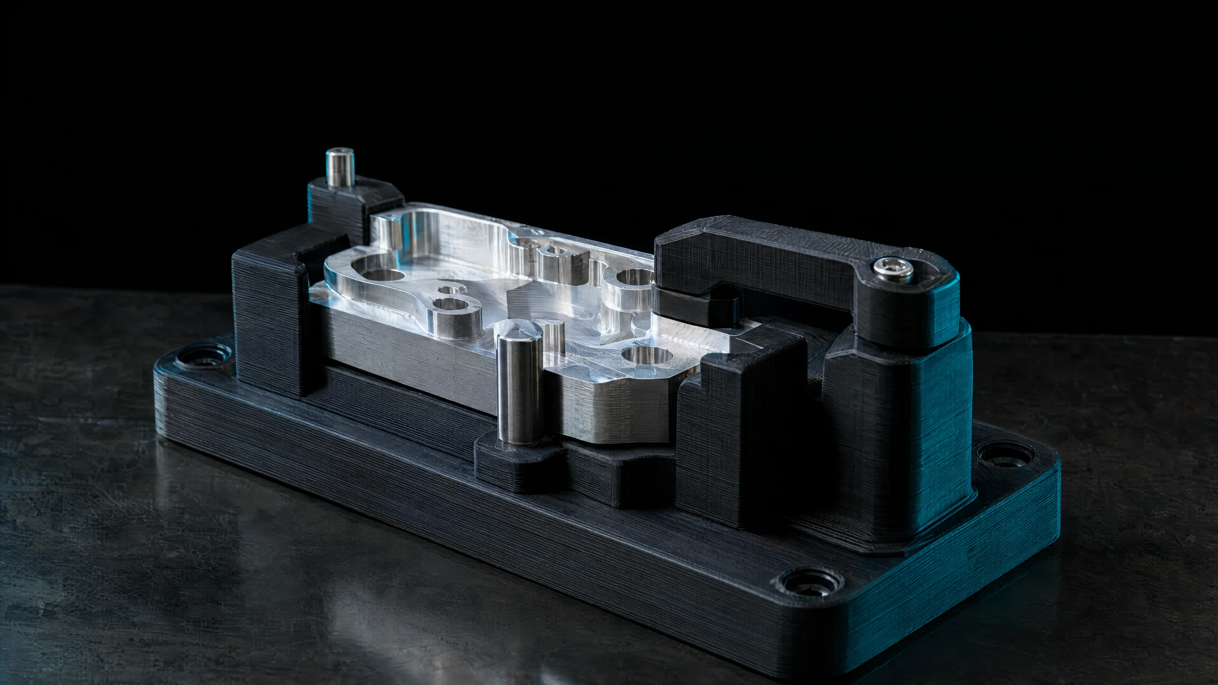 Dima stampata in 3D in materiale nero che tiene un pezzo in alluminio su un banco di lavoro
